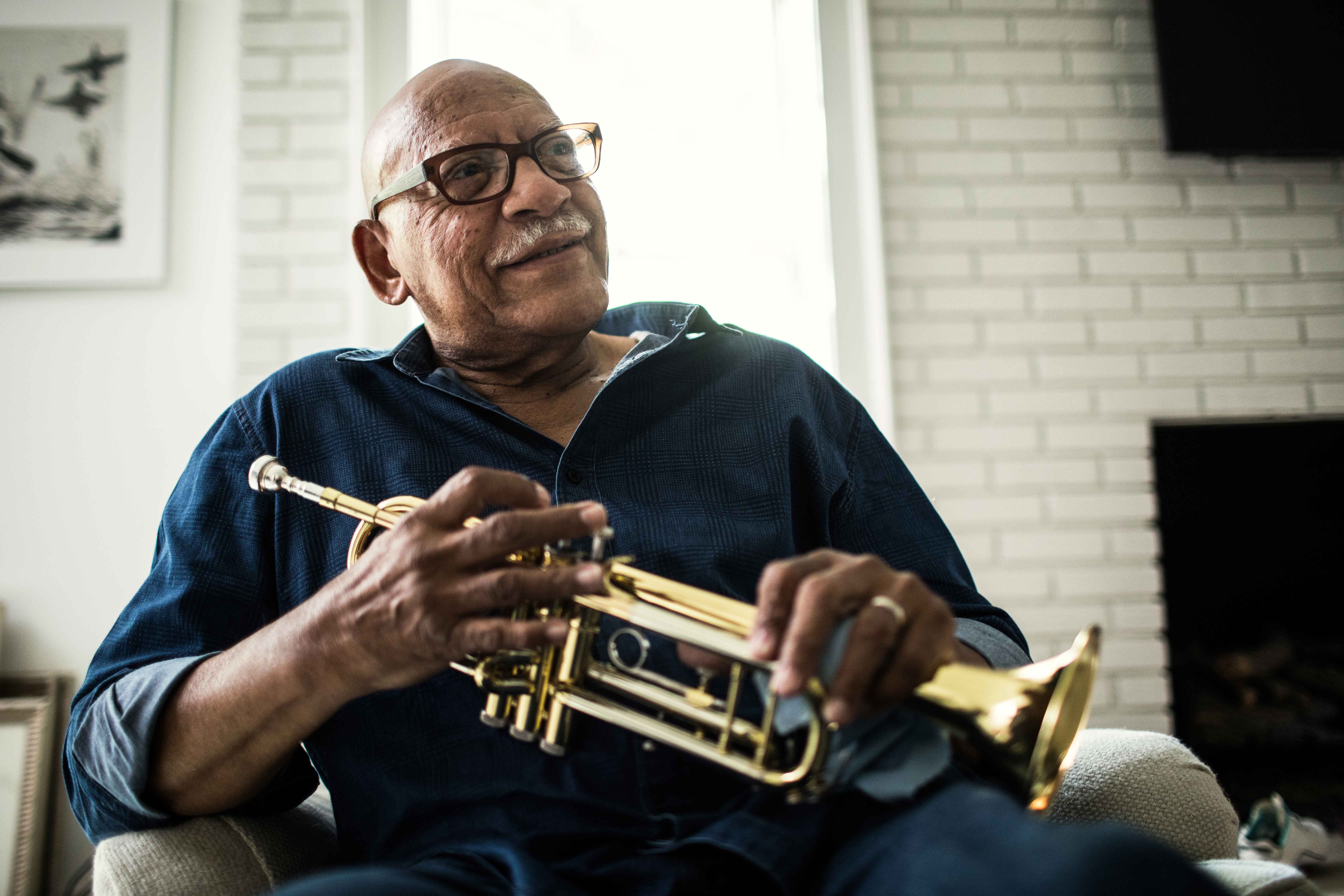 Photo of older African-American man with COVID-19 high risk factors playing his trumpet.